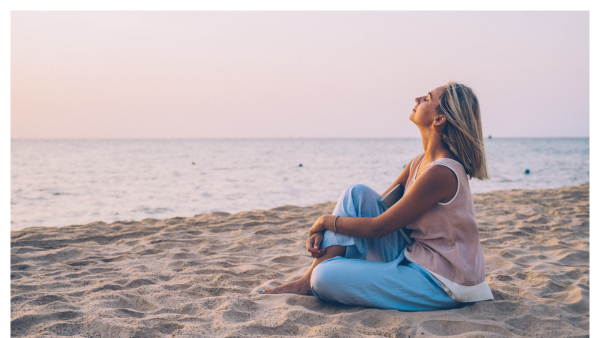 Woman sitting on the beach relaxing and taking in sunshine