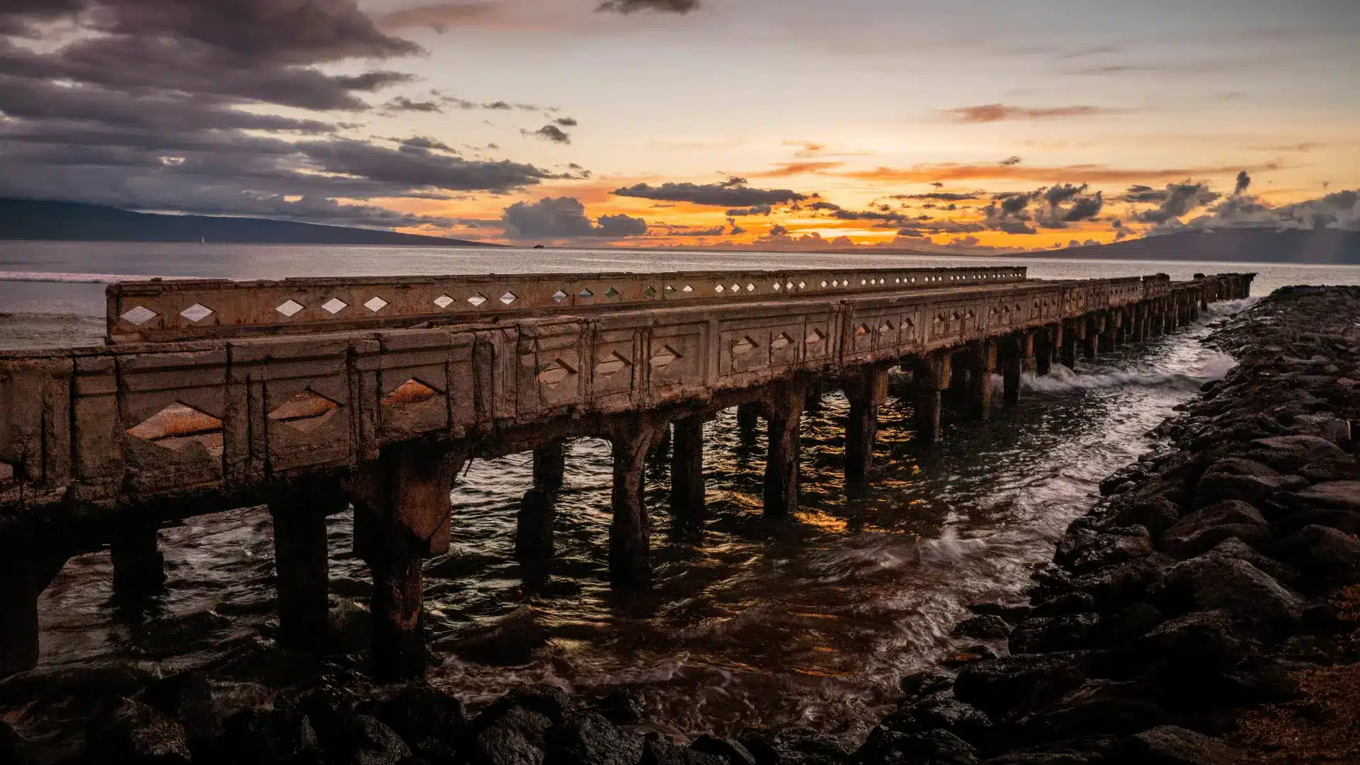 An old pier in Lahaina stretches out into the ocean at sunset