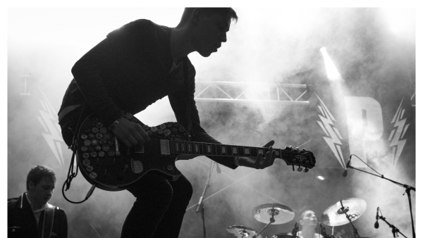 Black and white image of a guitarist on stage with smoke in the background