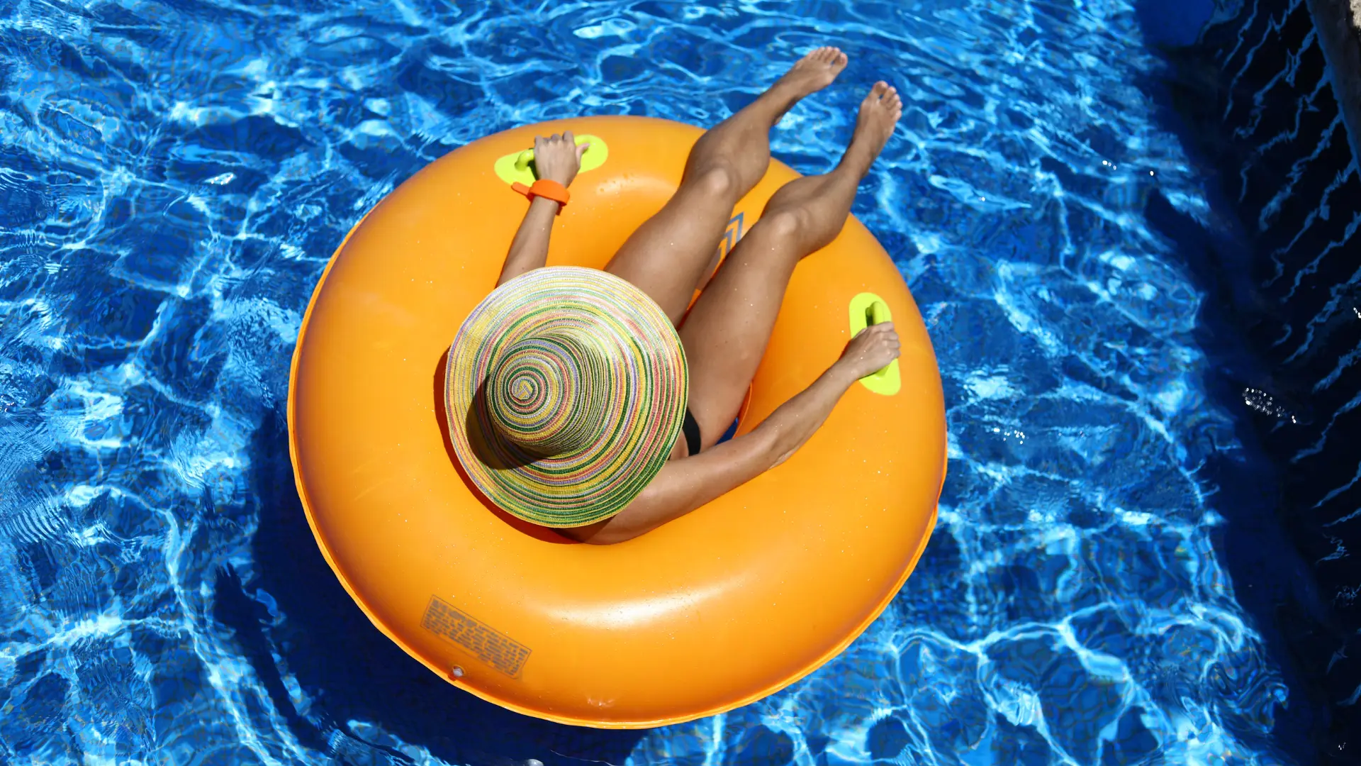 Photo of woman floating on a lazy river in a donut with a hat on