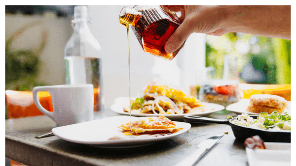 Someone pouring maple syrup on waffles at Cheeky's