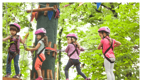 View of children along the zip line obstacle in the trees