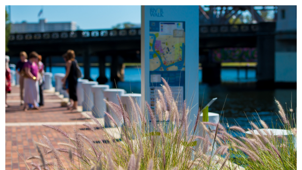 View of the Tampa Riverwalk with a sign and people in the background