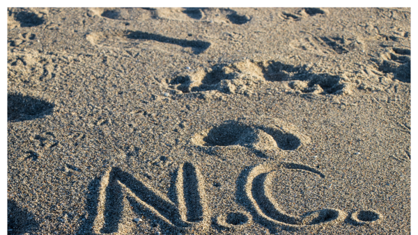 View of the initials NC drawn into sand on the beach